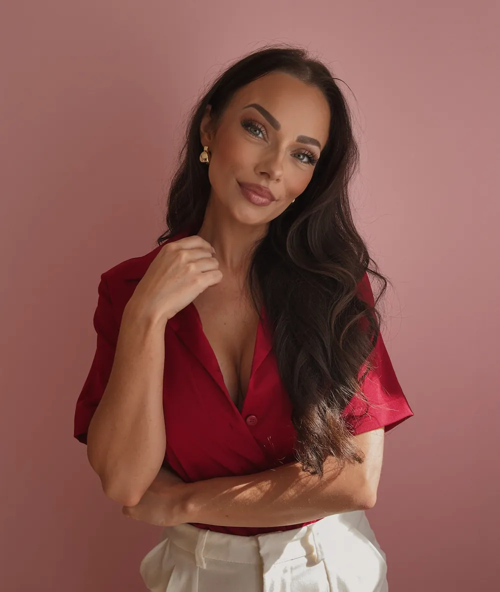 Ani Shanti in a cherry-red shirt against a pink wall